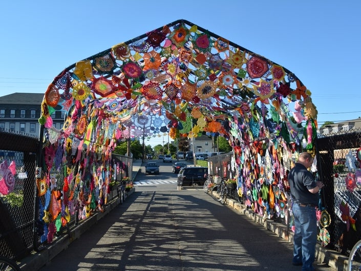 A blanket of crocheted pieces hangs over the pedestrian bridge between North and South avenues in downtown Natick.